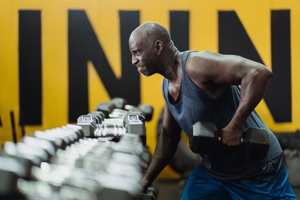 Experienced older lifter working with dumbbells in a gym, already active and training for performance