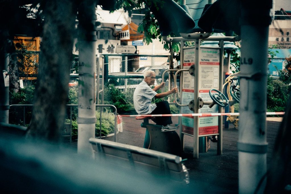 Older adult using outdoor exercise equipment in a Hong Kong park, training in a familiar setting