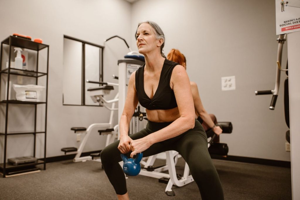 Older woman performing a kettlebell squat, the kind of progressive loading used in training for low bone density