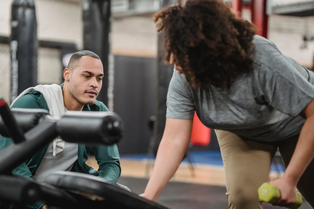 Personal trainer watching closely as a client performs a dumbbell exercise, correcting technique rep by rep
