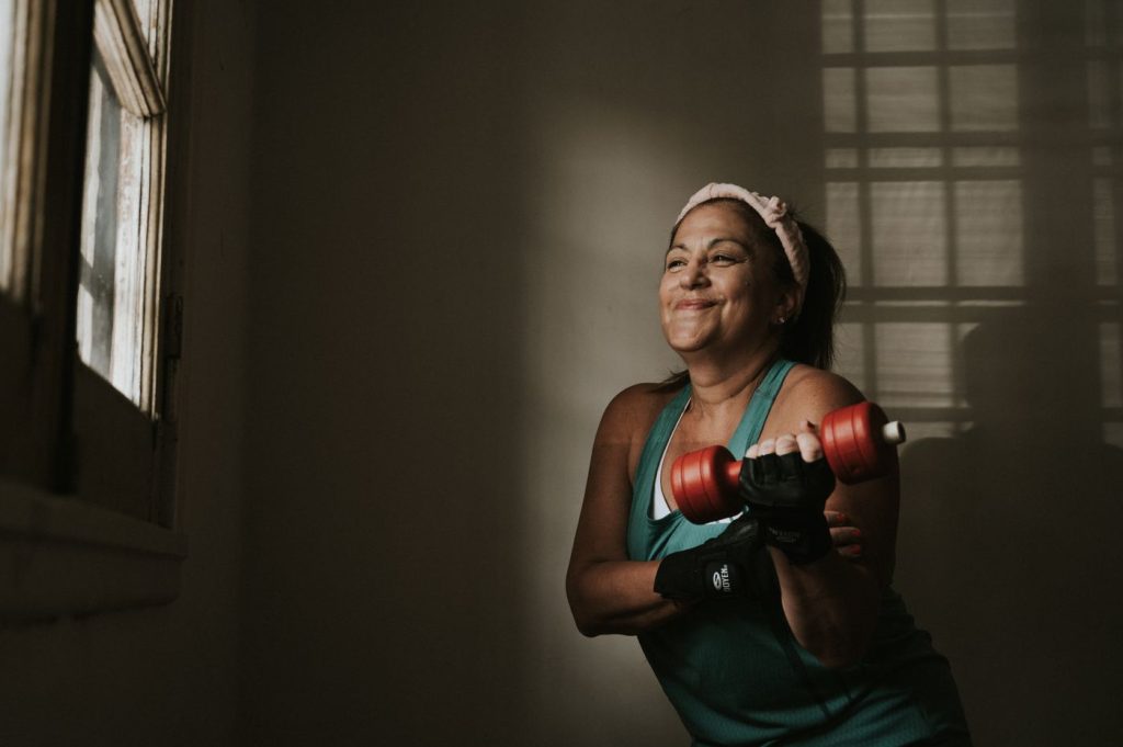 Woman in her fifties lifting dumbbells during a strength session, training through menopause and after